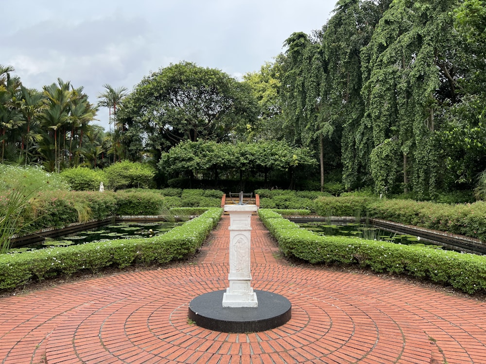 a brick walkway with a fountain and trees on either side of it