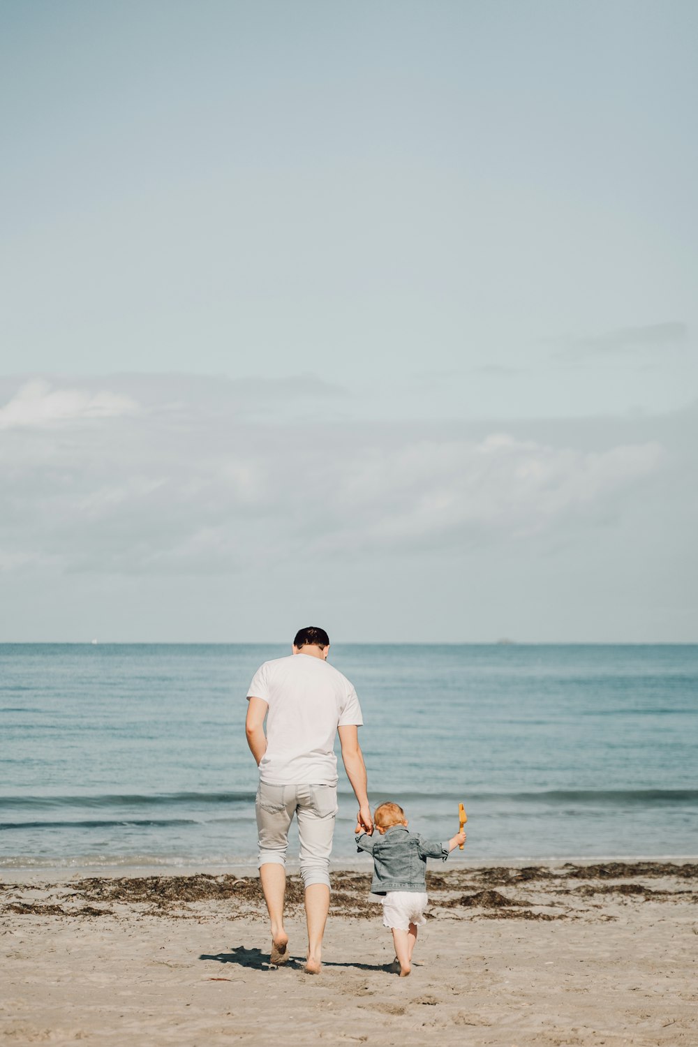 a man and a child walking on a beach