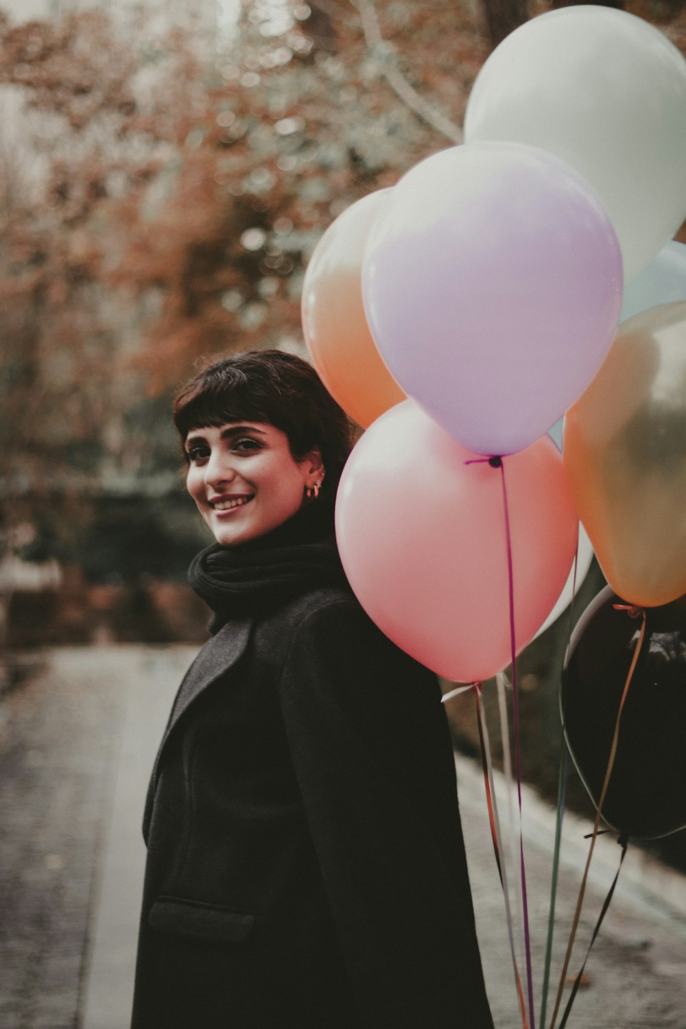 a woman holding a bunch of balloons