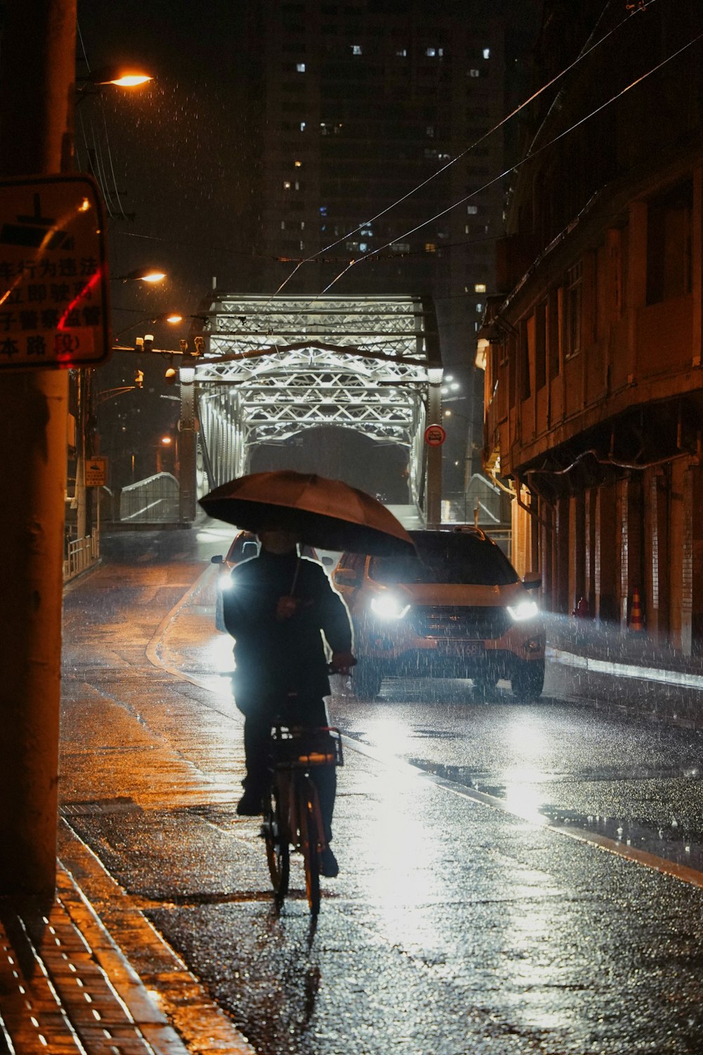 eine Person, die mit einem Regenschirm im Regen Fahrrad fährt