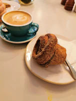A cozy café scene featuring a steaming cup of coffee and a freshly baked pastry on a crisp parchment napkin.