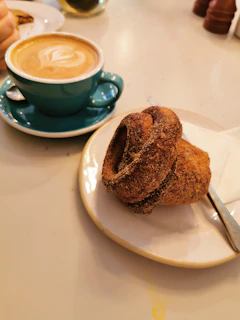 A cozy café scene featuring a steaming cup of coffee and a freshly baked pastry on a crisp parchment napkin.