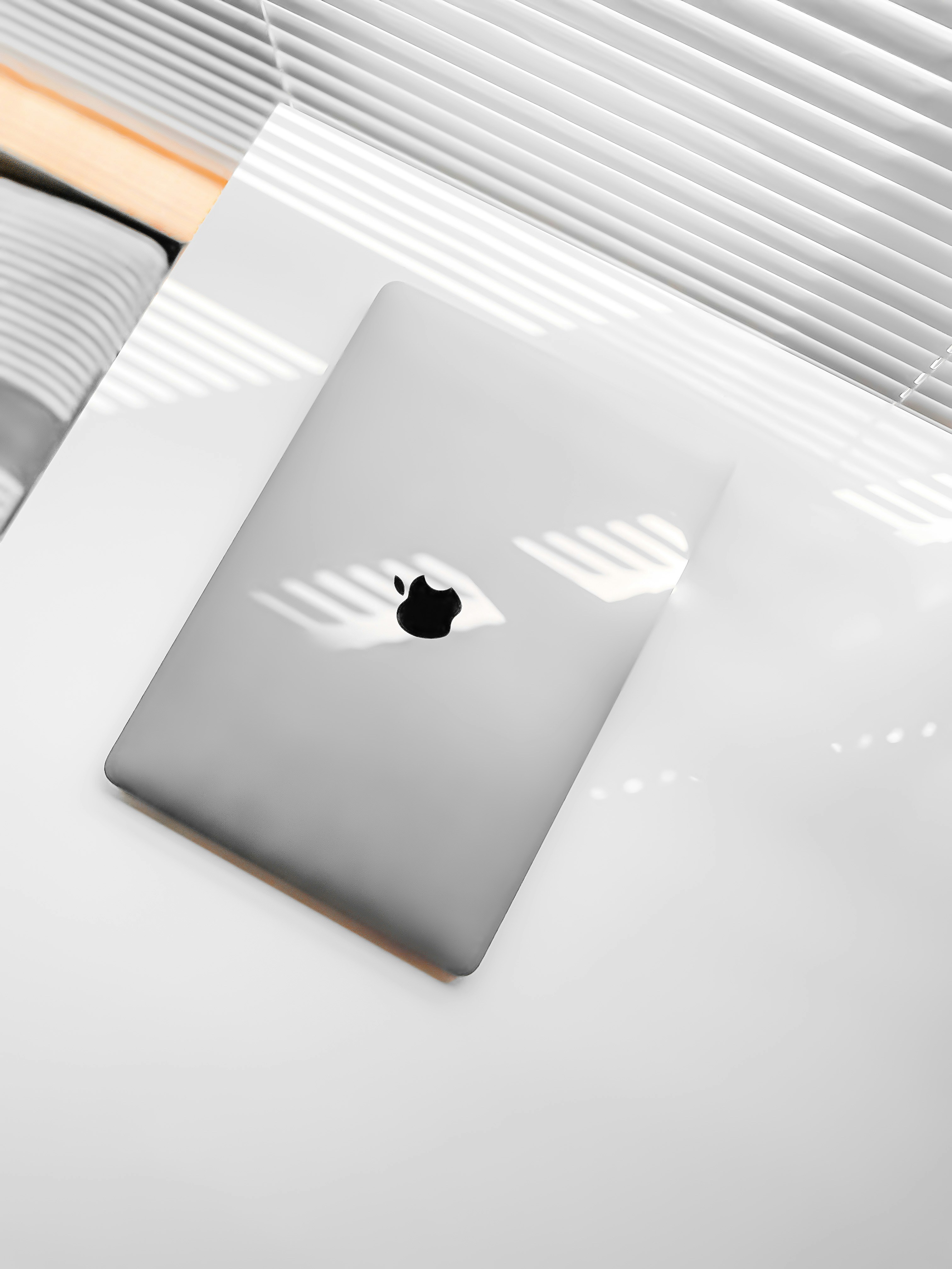MacBook laptop on white desk with natural window light