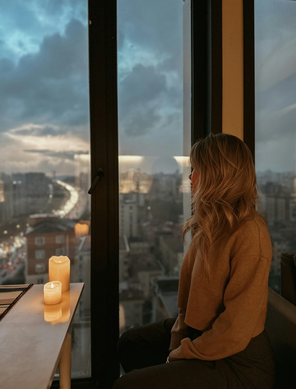 a person sitting on a window ledge looking out at a city