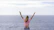 a woman with her arms raised in front of a body of water