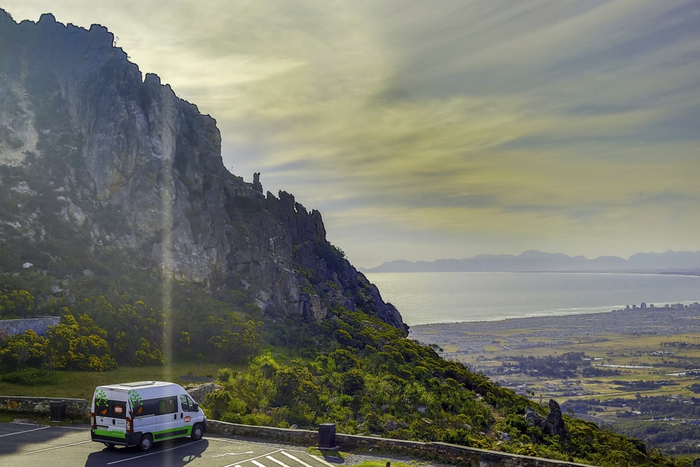 a van driving on a road next to a cliff