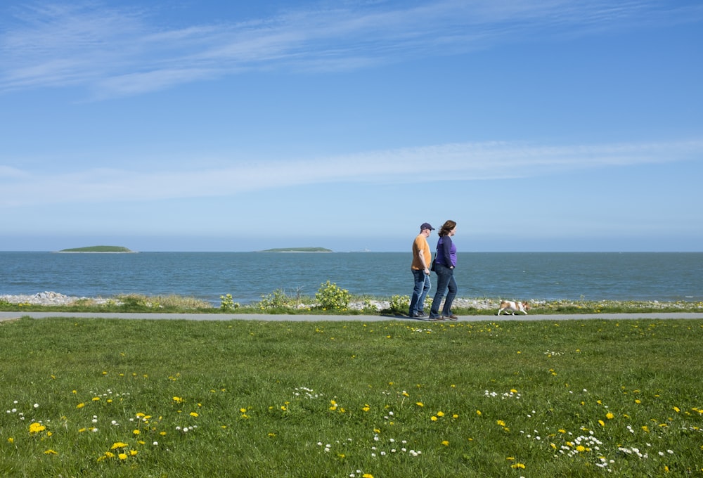 a man and woman standing on a path by a body of water