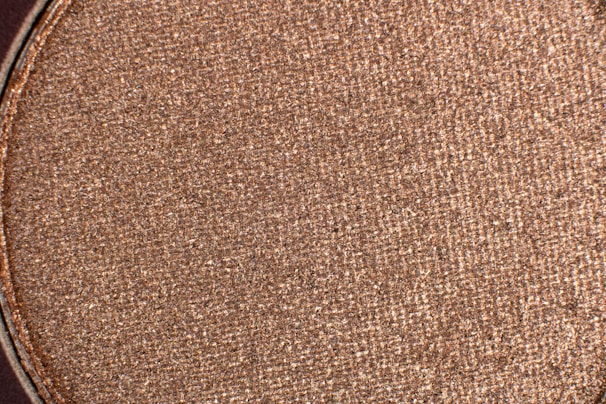 Close-up of shimmering mica powder in soft rose gold hues, ready for cosmetic blending.