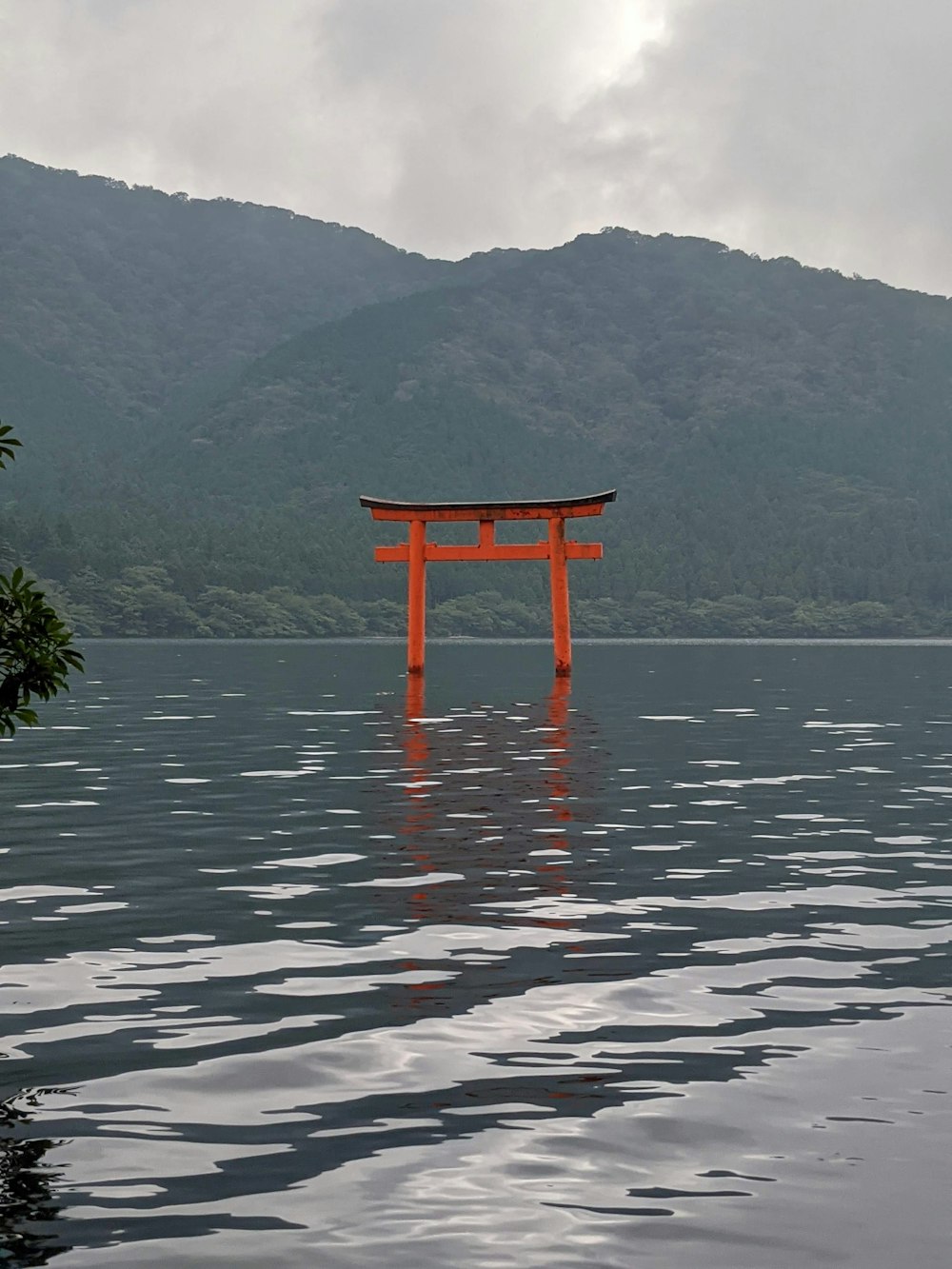 a red structure in a body of water with mountains in the background