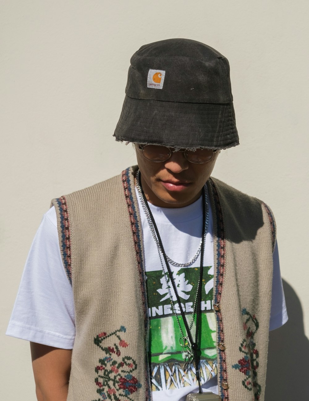 a young man wearing a hat and vest