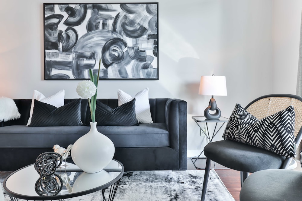 a living room with a black couch and a table with a vase with flowers on it