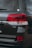 The image captures the rear section of a dark-colored vehicle, highlighting the V8 emblem and red tail lights. The car's glossy surface reflects the surroundings, and the image features a close-up of the tailgate area.