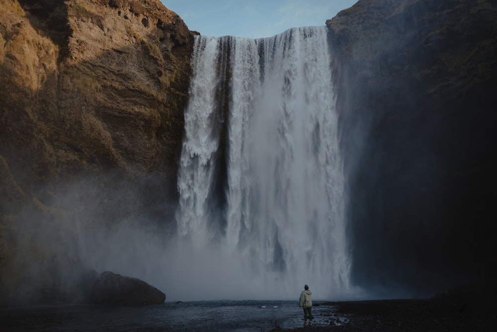 um homem em pé na frente de uma cachoeira
