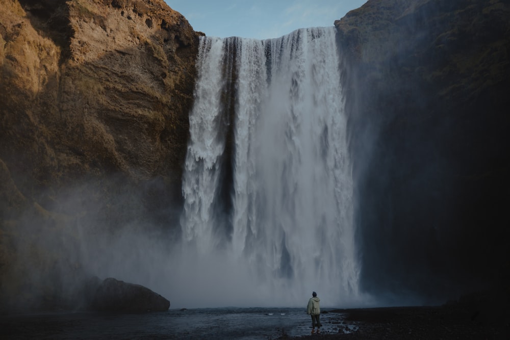 a man standing in front of a waterfall