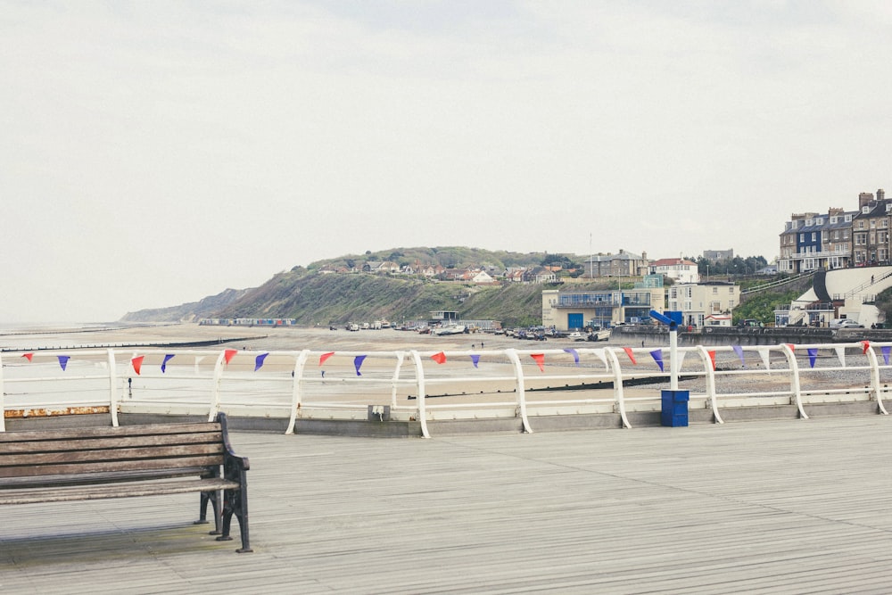 a beach with a bench and a body of water with buildings in the background