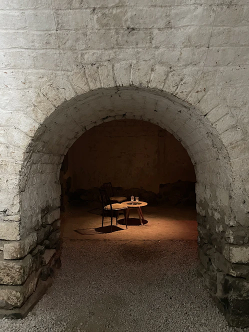 A dimly lit tavern scene with a mysterious guide singing softly, surrounded by shadowy figures listening intently.