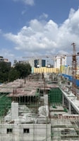 Wide shot of a construction site with cranes and workers assembling structural frameworks.