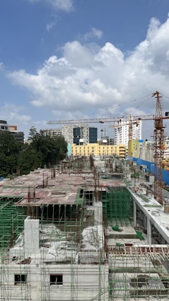 Construction workers collaborating on a building site with cranes and concrete structures in the background.