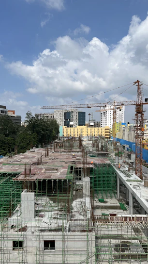 Construction workers collaborating on a building site with cranes in the background.