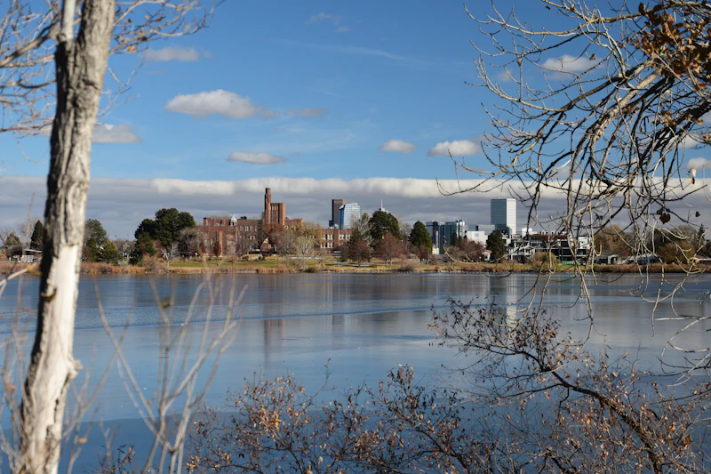 Lake ringed by trees with buildings on the far shore