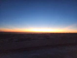 Panoramic view of flat land stretching toward distant mountains at sunset.
