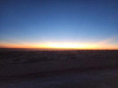Panoramic view of flat land stretching toward distant mountains at sunset.