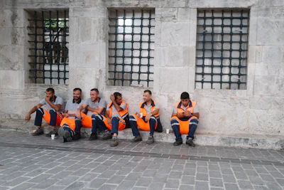 Operators wearing orange and yellow safety vests interacting during a break on the factory site.