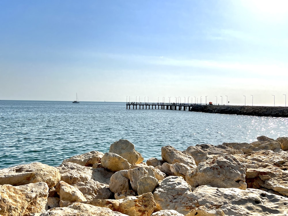 Una spiaggia rocciosa con un molo sullo sfondo