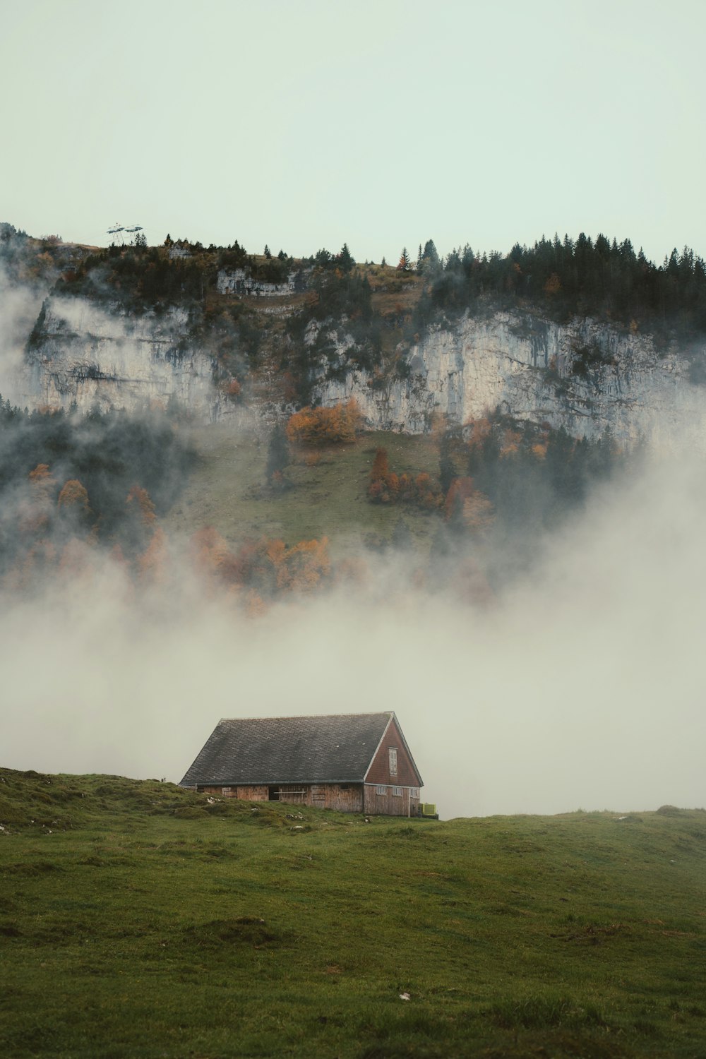 a house in a field with a large fire behind it