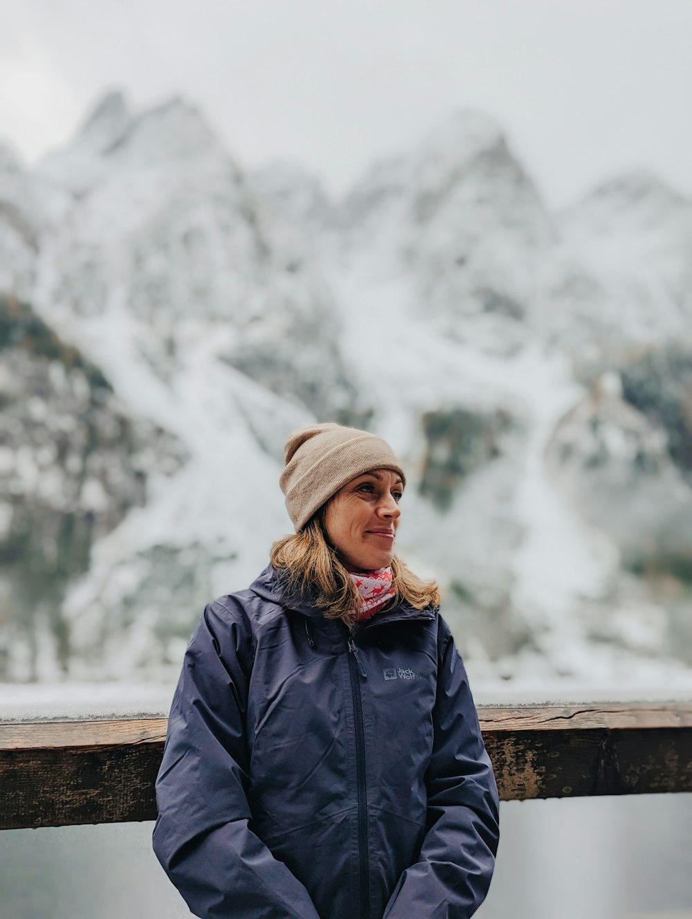 a person standing on a railing overlooking a snowy mountain