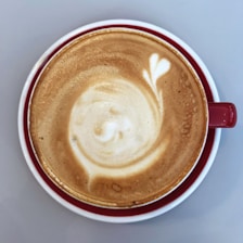 A close-up of a beautifully crafted coffee cup with latte art on a wooden table.