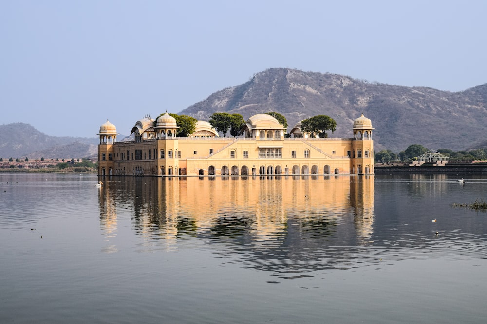 a large building with domed roofs by a body of water with Jal Mahal in the background
