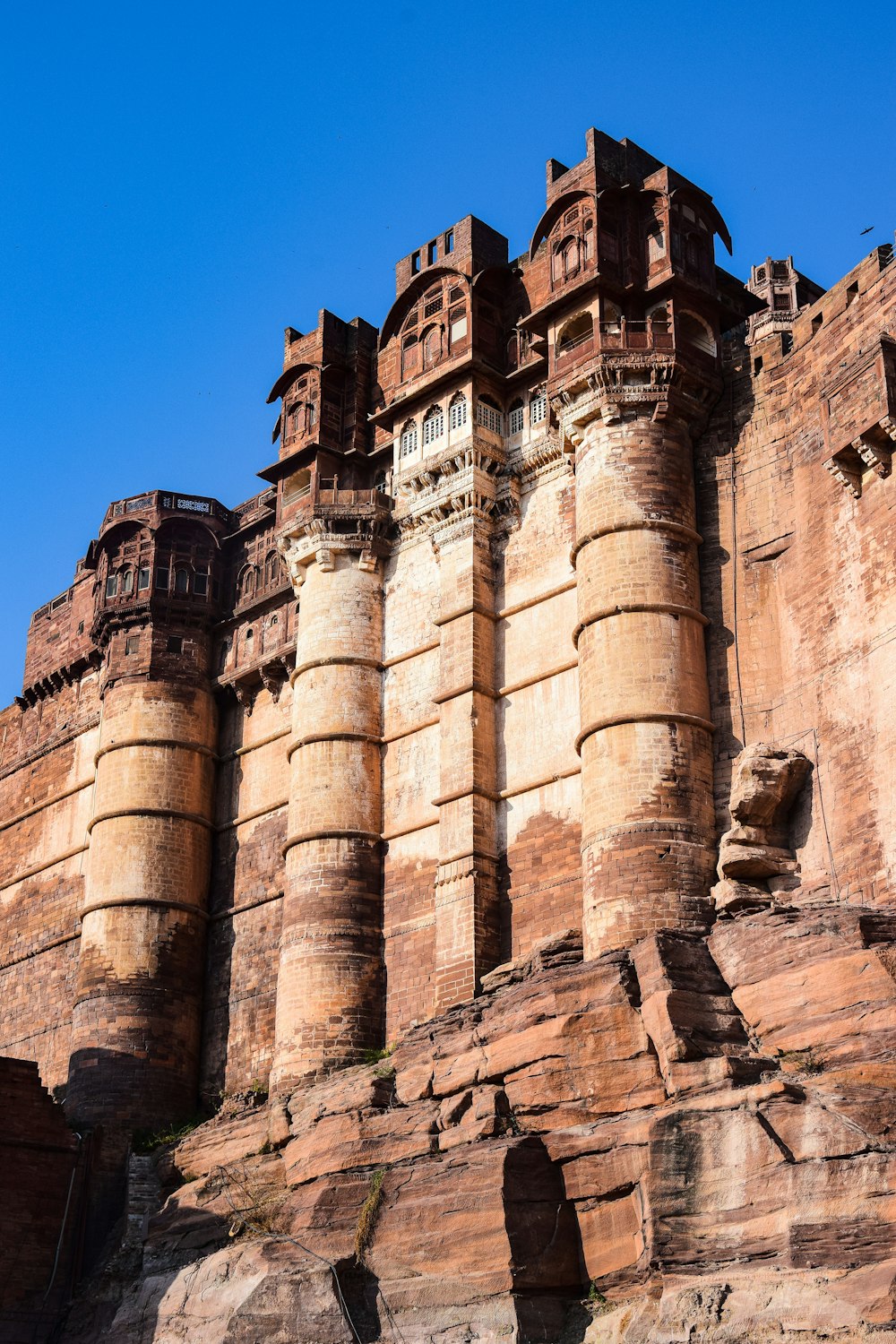 a large stone building with Mehrangarh Fort in the background