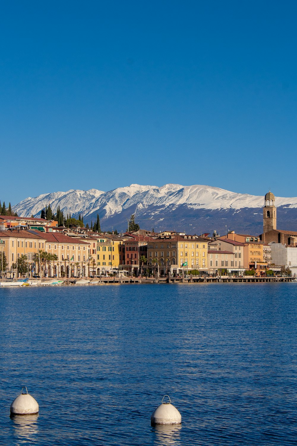 a body of water with buildings and mountains in the background