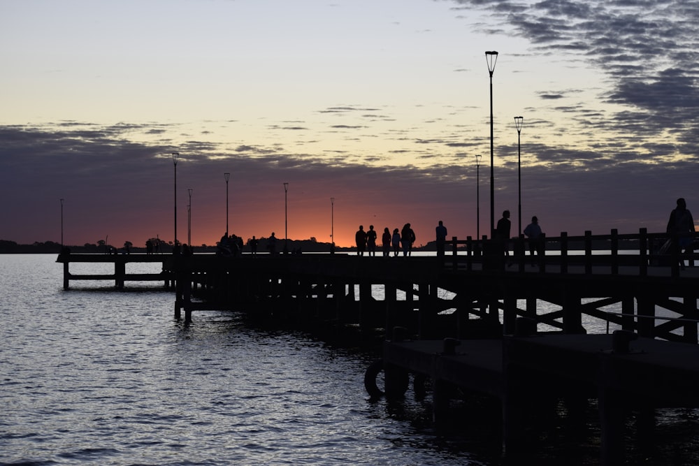 a group of people walking on a dock over water