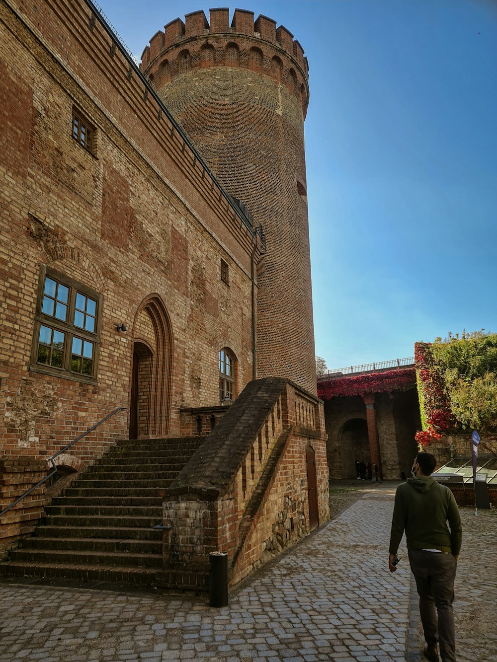 a person walking on a stone path next to a brick building