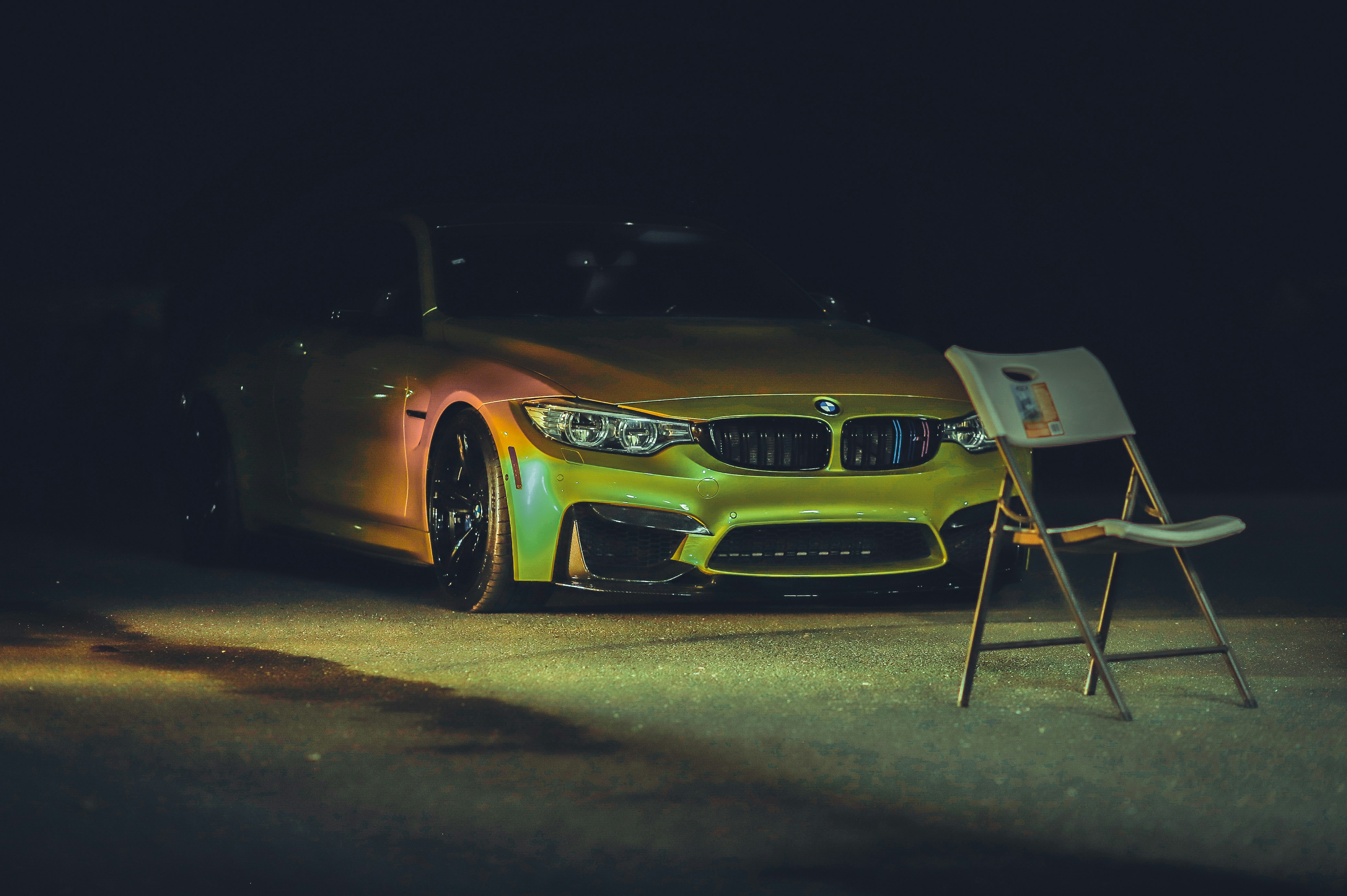 a yellow sports car parked next to a chair and a chair