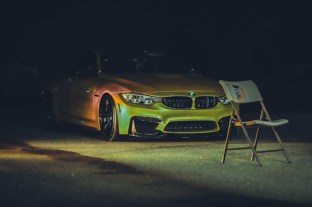 a yellow sports car parked next to a chair and a chair
