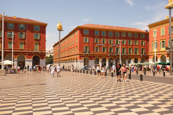 a group of people walking in a plaza in front of a building