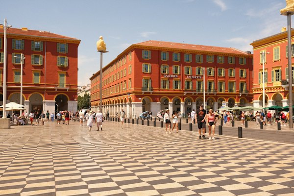 A group of people walking in a plaza in front of a building — Nice, France