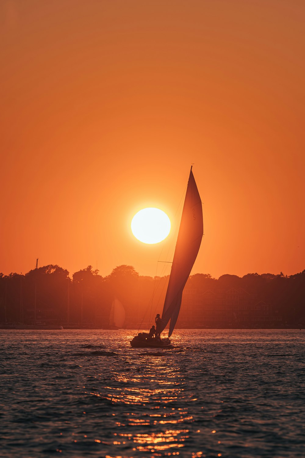 a boat in the water with a large sailboat in the background