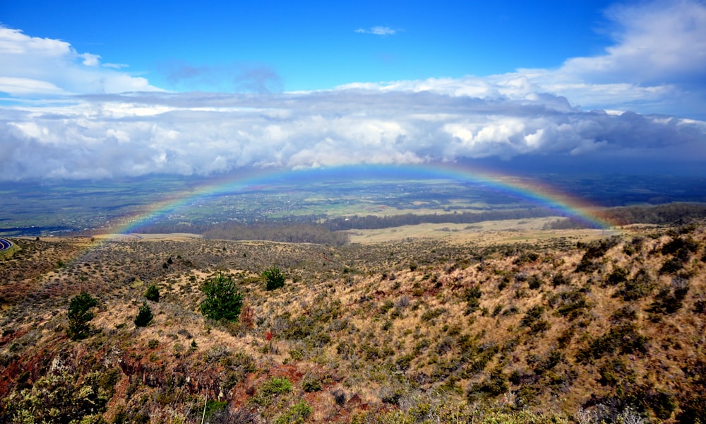 a landscape with hills and a rainbow