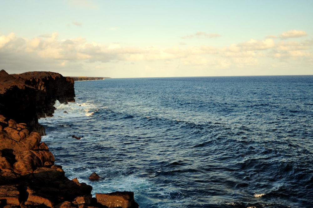 a rocky beach with a body of water in the background