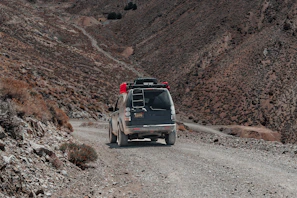 A rugged 4x4 vehicle loaded with supplies driving through dusty roads near a refugee camp
