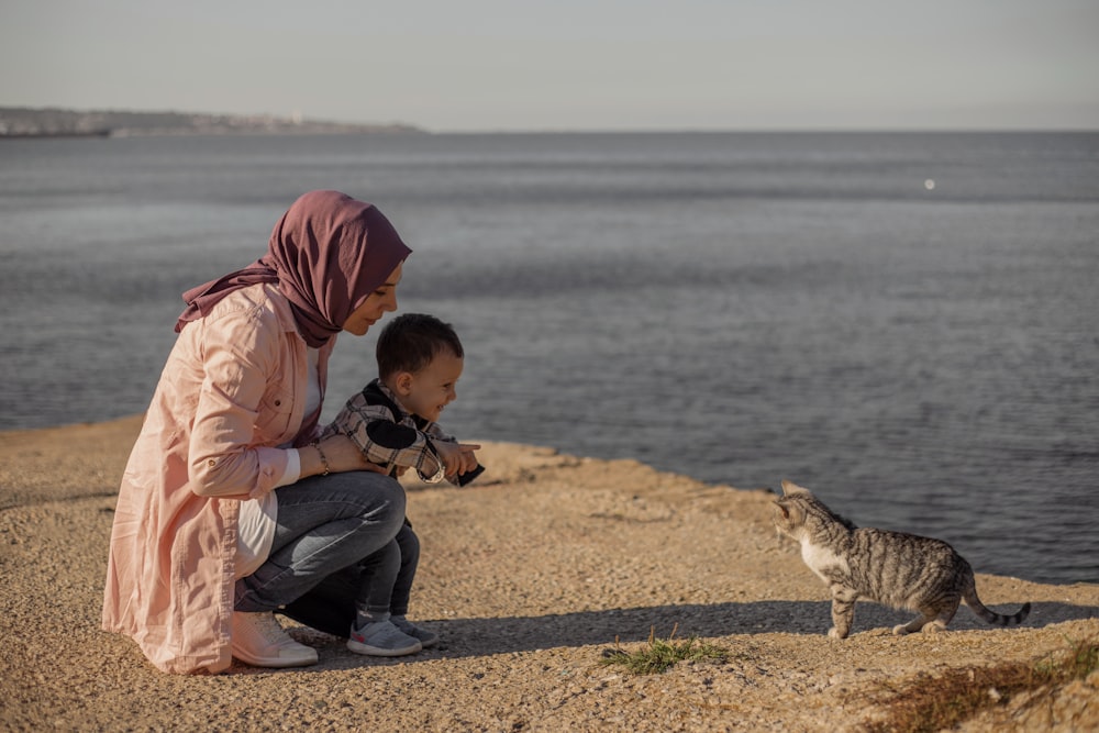 a person and a child looking at a fox on a beach