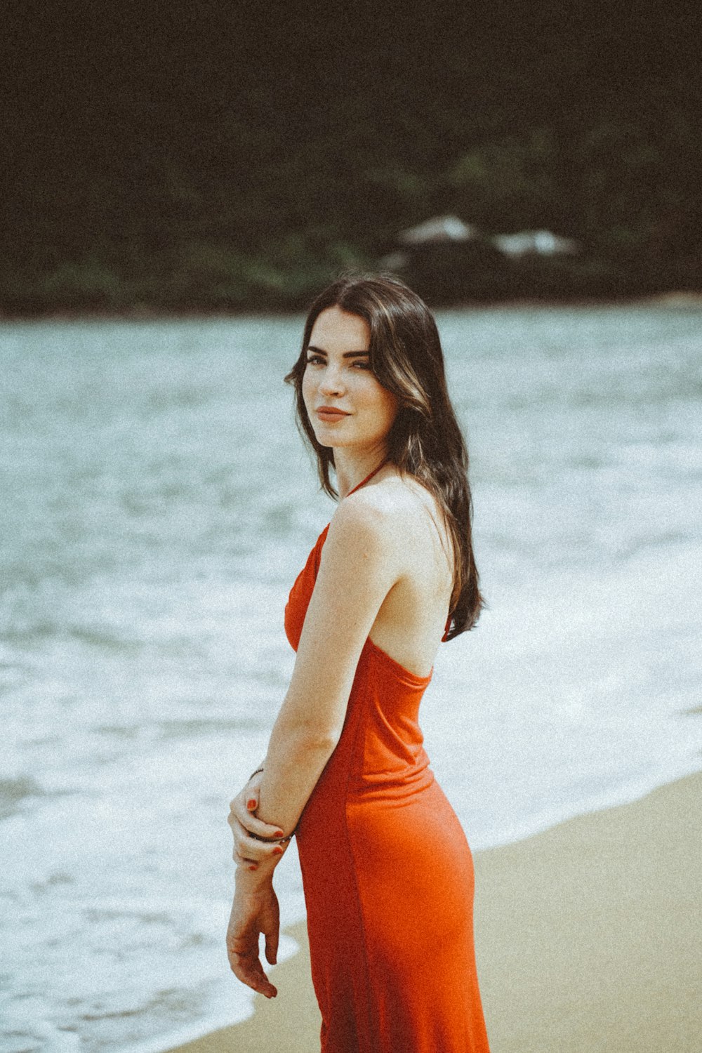 a woman in an orange dress on a beach