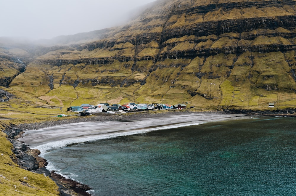 a beach with a body of water and a rocky cliff with a beach and houses