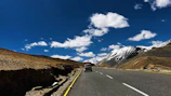 A cab driving along a scenic mountain highway under a clear blue sky.