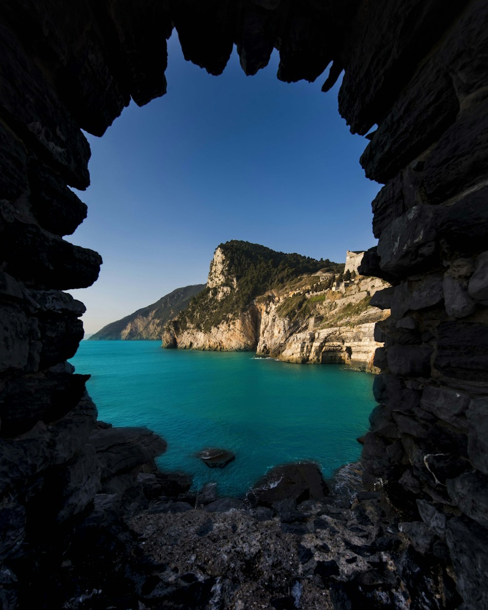 a view of a blue sea through a cave