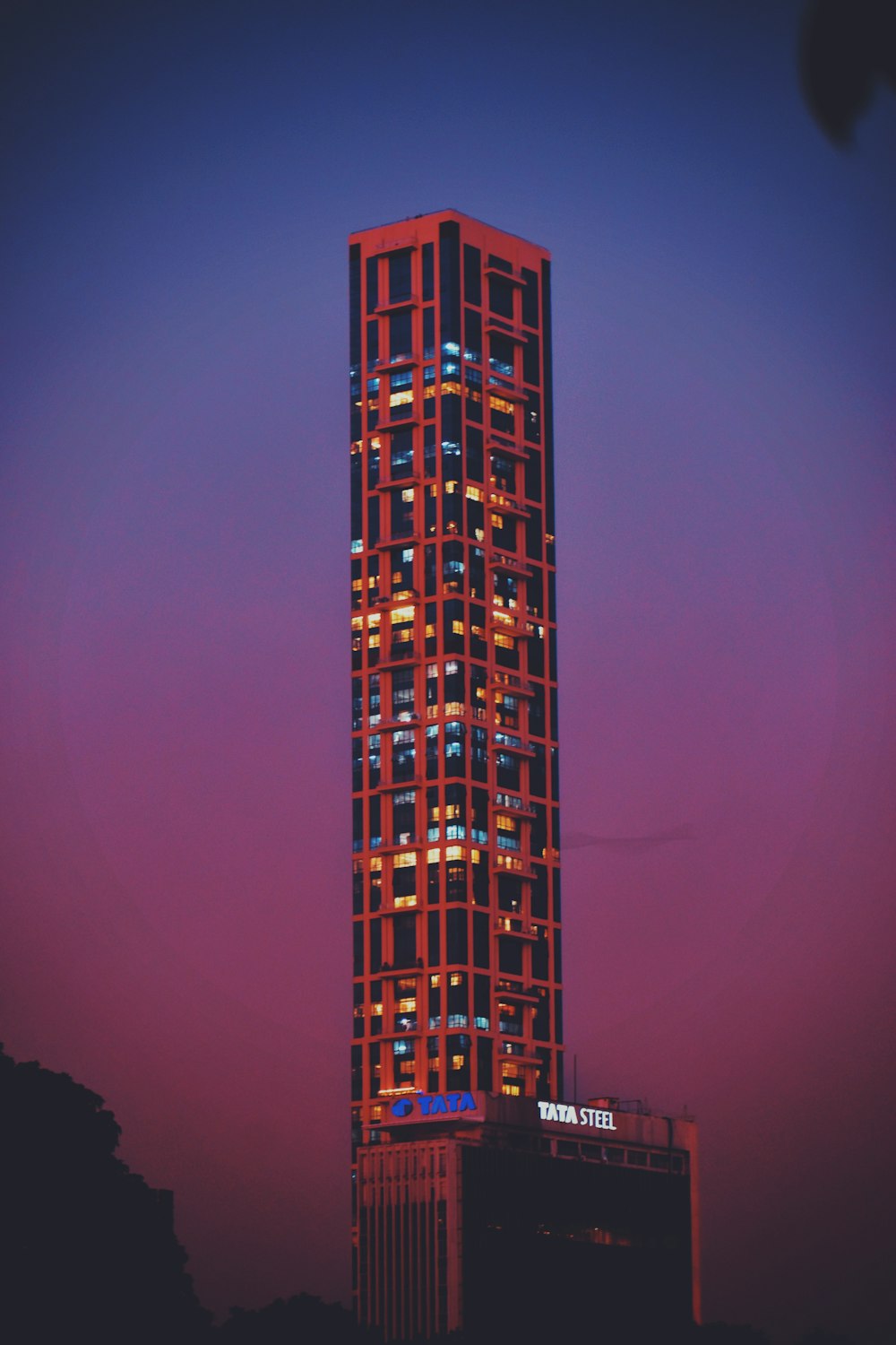 a tall building with a red and blue sky